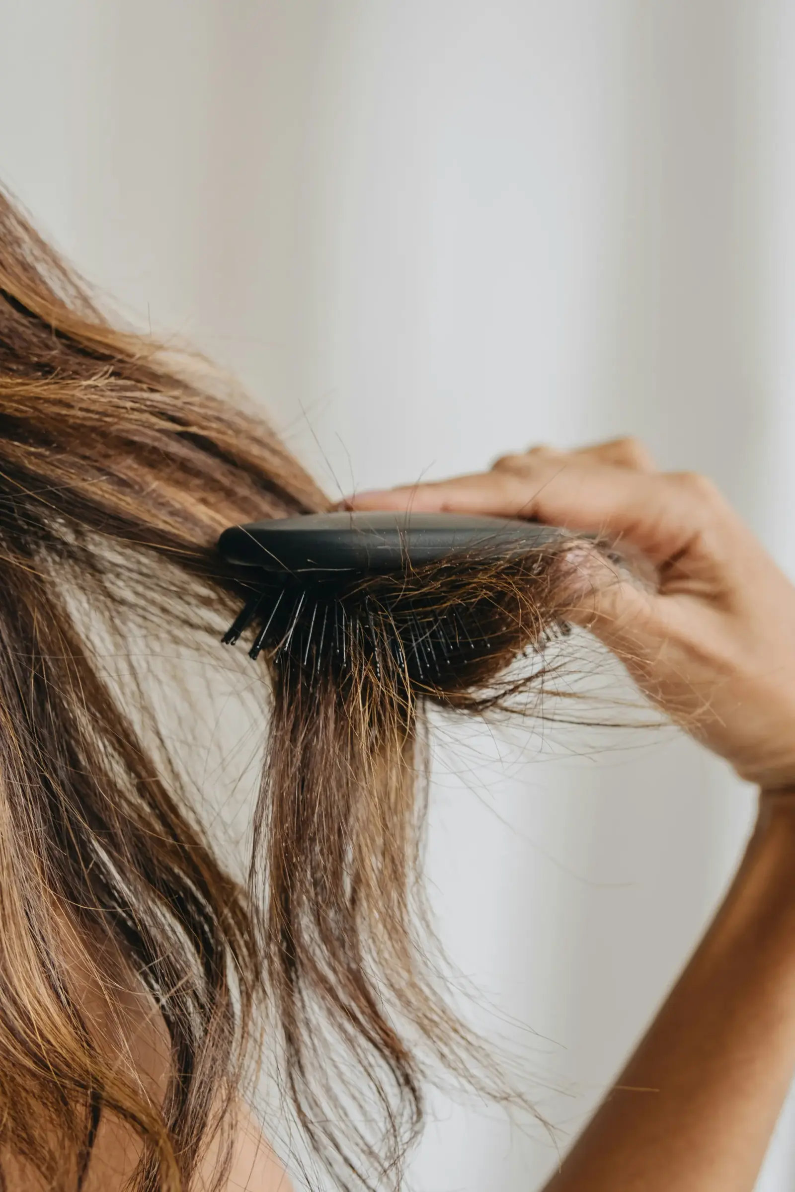 Person examining thinning hair at the part